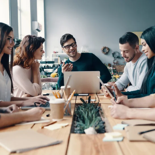 A group of skilled social media marketing specialists discussing marketing techniques to improve ROI.